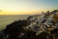 Panoramic skyline scene in sunset light of Oia windmill and white building townscape along island natural mountain facing ocean Royalty Free Stock Photo