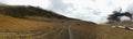 Panoramic of sloping grassland with deep valley on the right