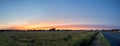 Panoramic sunset over a picturesque farm in rural agricultural America with a road leading into the distance Royalty Free Stock Photo