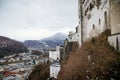 Panoramic top scenery of old town, viewpoint at Hohensalzburg Fortress, during cloudy and gloomy winter day, mountains under snow Royalty Free Stock Photo