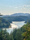 Panoramic top view of mountain river reflecting sunlight surrounded by dense green forest under clear sky Royalty Free Stock Photo