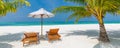 Panoramic tropical island scenery, two sun beds, loungers, umbrella under palm tree. White sand, sea view with horizon Royalty Free Stock Photo