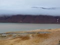 Panoramic view of arctic desert landscape and arctic ocean. Cloudy sky and mountains in the background. Svalbard, Norway