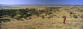 Panoramic view as Masai Warrior in red surveying landscape of Lewa Conservancy, Kenya, Africa with Mount Kenya Royalty Free Stock Photo