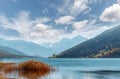 Panoramic view of beautiful autumn scenery in the Alps with snowy mountain summits reflecting in crystal clear mountain lake on a Royalty Free Stock Photo