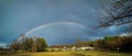Panoramic view of beautiful rainbow in blue sky over a house with lush green garden Royalty Free Stock Photo