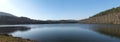 Panoramic view on blue calm water of forest lake, fish pond Kunraticky rybnik with birch and spruce trees growing along Royalty Free Stock Photo