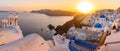 Panoramic view of blue domed churches and bell tower with warm sunset light in Oia, Santorini, Greece Royalty Free Stock Photo