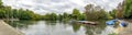Panoramic view of a boating lake with paddle boats parked and park cafe outdoor tables, Battersea Park, London Royalty Free Stock Photo
