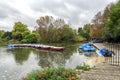 Panoramic view of a boating lake with paddle boats parked and park cafe outdoor tables, Battersea Park, London, United Kingdom Royalty Free Stock Photo