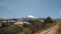 Panoramic view of the Cayambe volcano in the middle of planted green fields during a sunny day with blue sky
