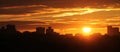 Panoramic view of cityscape with silhouette of city skyline against setting sun