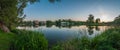 Panoramic view from the coast through a lake in a city park to an old building. evening summer landscape. coastal reeds. clear sky Royalty Free Stock Photo