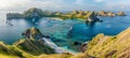 Panoramic view of comically shaped island with lush hills and beaches, surrounded by sea, at dawn