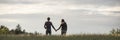 Panoramic view on couple holding hands in field