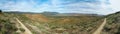 A panoramic view of a desert landscape with a dirt road running through it Royalty Free Stock Photo