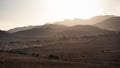 Panoramic view of the desert at sunset time, mountain layers in a misty landscape, sun behind the hills, dry landscape by the Royalty Free Stock Photo