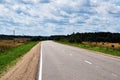 Panoramic view of the deserted road. The road runs through fields of mown grass.