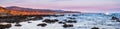 Panoramic view of the dramatic Pacific Ocean coastline at sunset, during low tide, Santa Cruz mountains in the background; San