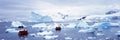 Panoramic view of ecological tourists in inflatable Zodiac boat with glaciers and icebergs in Paradise Harbor, Antarctica