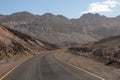 Death Valley - Panoramic view of endless empty road leading to colorful geology of multi hued Artist Palette rock formations
