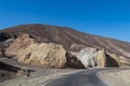 Death Valley - Panoramic view of endless empty road leading to colorful geology of multi hued Artist Palette rock formations