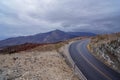 Panoramic view of endless empty road leading to colorful geology of multi hued rock formation and hills of Panamint mountains