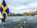 Panoramic view from the excursion boat with the flag of Sweden on the beautiful buildings of Stromkajen in the center of Stockholm Royalty Free Stock Photo