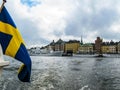Panoramic view from the excursion boat with the flag of Sweden on tourist boats and waterfront houses in Gamla Stan. Stockholm Royalty Free Stock Photo