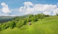 Panoramic view on green grass hills with haystack under white clouds. Beautiful rural landscape Royalty Free Stock Photo