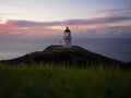 Panoramic view of historic white Cape Reinga lighthouse landmark on oceanside clifftop during sunset in New Zealand Royalty Free Stock Photo