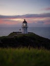 Panoramic view of historic white Cape Reinga lighthouse landmark on oceanside clifftop during sunset in New Zealand Royalty Free Stock Photo