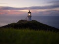 Panoramic view of historic white Cape Reinga lighthouse landmark on oceanside clifftop during sunset in New Zealand Royalty Free Stock Photo