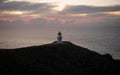 Panoramic view of historic white Cape Reinga lighthouse landmark on oceanside clifftop during sunset in New Zealand Royalty Free Stock Photo