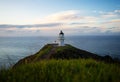 Panoramic view of historic white lighthouse landmark perched on oceanside clifftop Cape Reinga Northland New Zealand Royalty Free Stock Photo