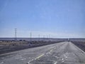 Panoramic view of a huge row of high-voltage towers running alongside a road in the desert Royalty Free Stock Photo