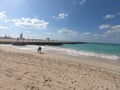 Panoramic View of Jumeirah Beach and Burj Al Arab and View of Pier. Woman picking up Shells at beach