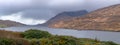 Panoramic view on lake in Irish mountains during stormy weather, green bush.