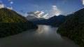 Panoramic view of Lake Ritsa against the backdrop of mountains in Abkhazia. The sun is hiding behind a mountain.