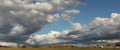 Panoramic view of large open dry drought affected farm fields under stretching cloud filled blue skies over properties in rural