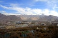 The panoramic view of Lhasa city, in front of Potala Palace and Palace square, with modern building and mountains, far away a Tib