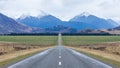 Panoramic view of long straight open icy road leading towards mountains in south island New Zealand Royalty Free Stock Photo