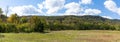 Panoramic view of a low mountain landscape, green field with trees, blue sky with clouds Royalty Free Stock Photo