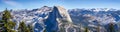 Panoramic view of the majestic Half Dome and the surrounding wilderness area with mountain peaks and ridges still covered by snow