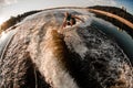 panoramic view of man in turquoise life jacket jumping on wakeboard over splashing wave Royalty Free Stock Photo