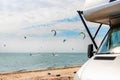 Panoramic view of many surf board kite riders on sand beach watersport spot on bright sunny day against rv camper van Royalty Free Stock Photo