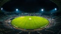 Panoramic view of a massive, empty cricket stadium pitch glowing vibrantly under powerful floodlights during a dark night event Royalty Free Stock Photo