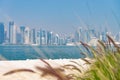 Panoramic view of modern skyline of Doha with green grass and beach foreground. Concept of healthy environment