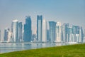 Panoramic view of modern skyline of Doha with green grass foreground. Concept of healthy environment