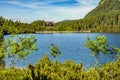 Panoramic view of the Morskie Oko mountain lake surrounding larch, pine and spruce forest with Schronisko przy Morskim Oku shelter